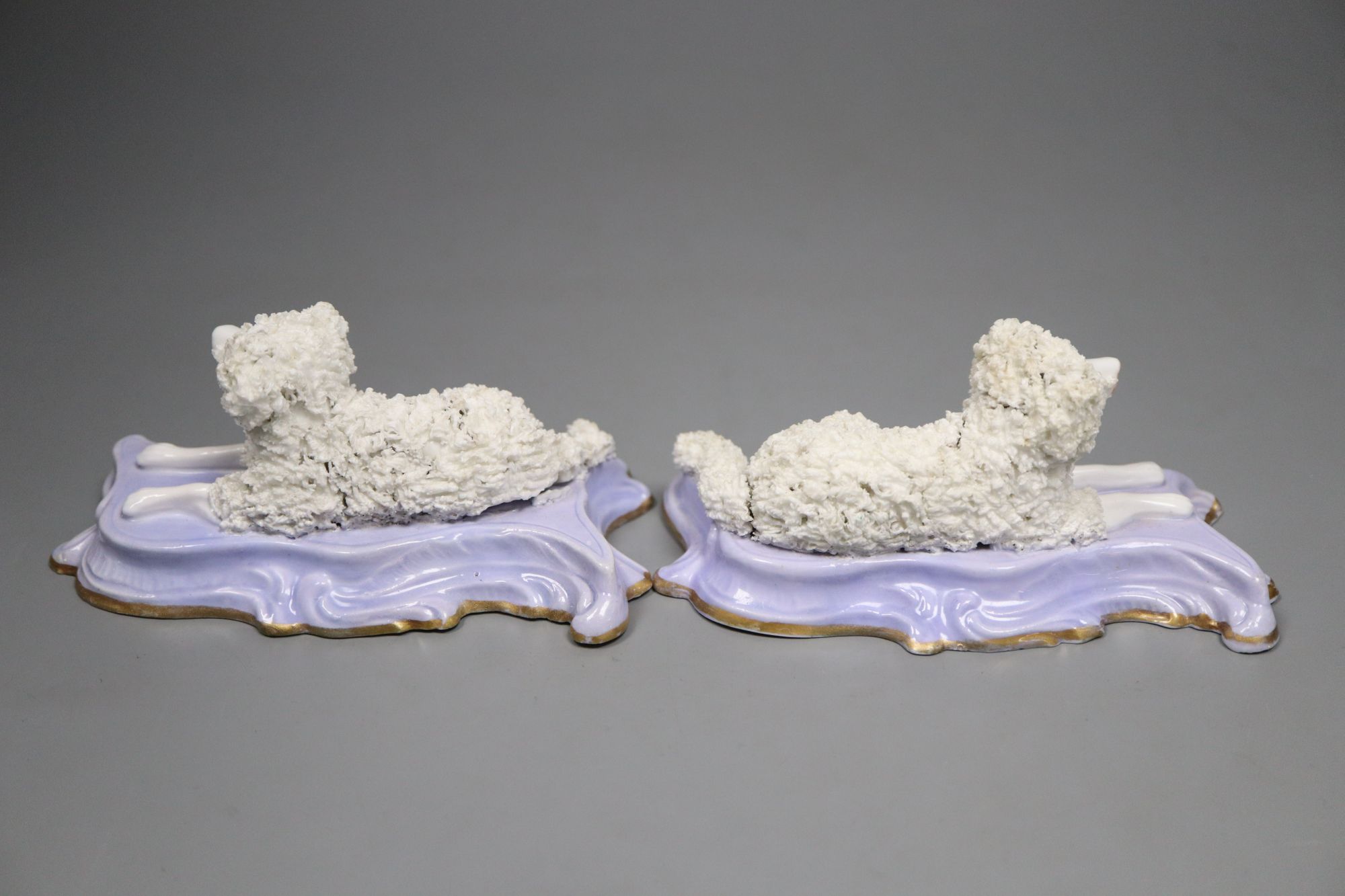 A good pair of Staffordshire porcelain figures of recumbent poodles, c.1835-50, 12.2cm long, lavender ground scrolled bases